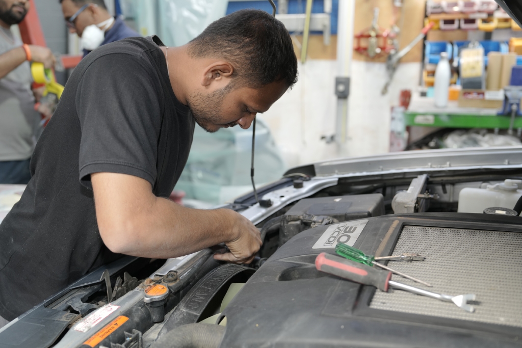 Technician working under the bonnet at Atmiya Auto Center